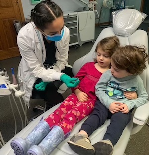 A photo of two children getting dental care